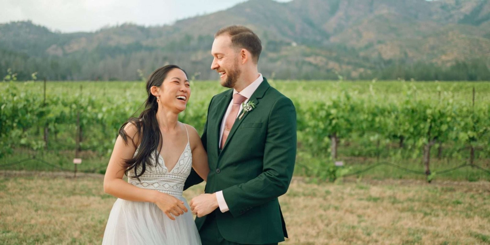 Playful newlywed couple embracing by the vineyard